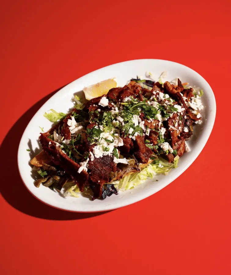 Tlayuda with grilled asada, lettuce, queso fresco and cilantro